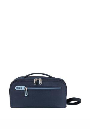 Borsa da toilette compatta blu navy con tasca frontale con cerniera, doppia cerniera superiore, maniglia laterale e logo American Tourister sulla tasca frontale.