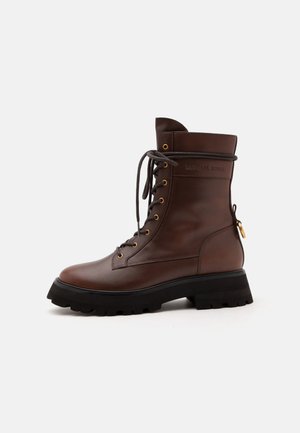 Dark brown leather lace-up combat boot with black chunky sole and gold eyelets, side zip, and embossed brand name near the ankle.