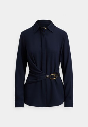 Tumši zila garroku krekls ar apkakli, priekšpusē tinuma dizains un melns jostasiksna ar zelta sprādzi un kniedes akcentiem. Mīksts auduma tekstūra.