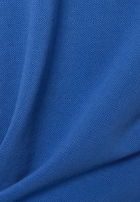 Tkanina tekstylna w jednolitym, jasnoniebieskim kolorze o gładkiej, nieco teksturowanej powierzchni z subtelnymi wzorami dzianinowymi oraz zwisającym wyglądzie.