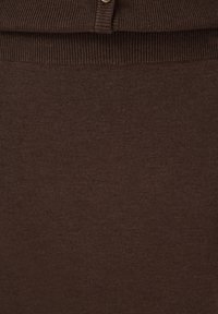 Gros plan sur un tissu tricoté côtelé marron avec une couture boutonnière en haut, montrant la texture et les détails de couture.