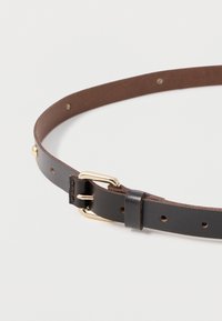 Černý kožený pásek s hladkým povrchem, zlatě zbarvenými kovovými detaily a několika otvory pro nastavení délky. Obsahuje prošívaný detail na přezce.