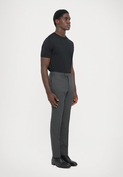 Camiseta negra de manga corta, diseño ajustado, combinada con pantalones grises de corte elegante, textura suave, complementada con zapatos negros de cordones.