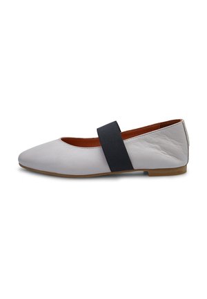 Zapato plano de cuero blanco con punta redondeada, que cuenta con una cinta elástica negra a lo largo del mediopié y una suela baja marrón.