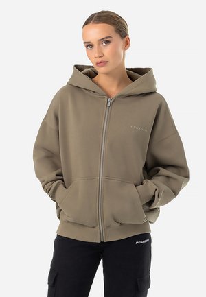 Khaki zip-up hoodie with a spacious hood, front pockets, ribbed cuffs, and a small logo on the left chest. Soft fabric and relaxed fit.