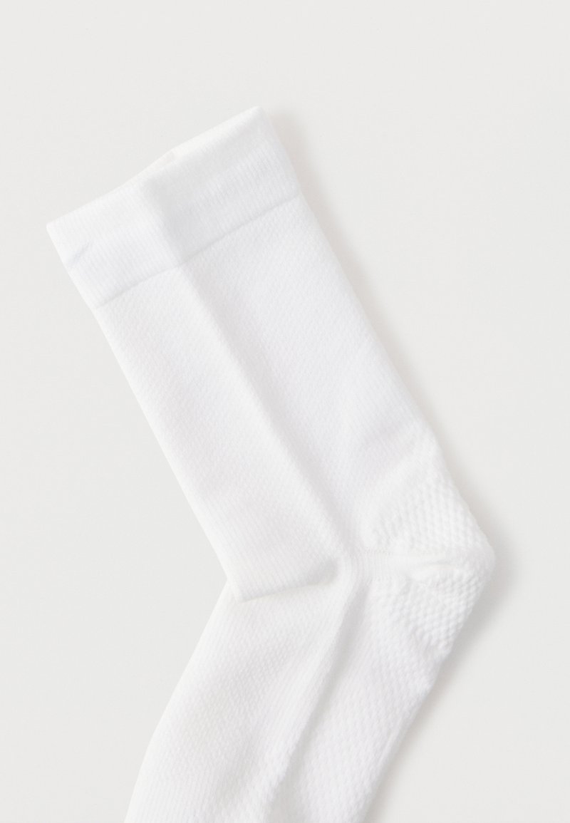 White cotton sock with a smooth texture, ribbed cuff, and reinforced toe. Features a subtle diamond pattern along the body.