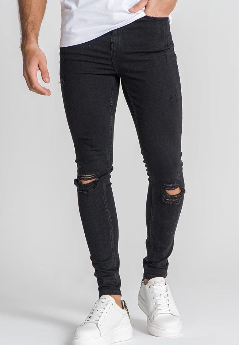 Vaqueros skinnies negros con desgarros en las rodillas, hechos de mezclilla, combinados con zapatillas de plataforma blancas. Camiseta blanca lisa.