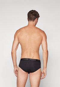 Schwarze Herrenunterwäsche mit einem strukturierten Bund, der das Puma-Logo zeigt. Das Material wirkt glatt, sitzt eng anliegend und hat keine zusätzlichen Muster oder Akzente.