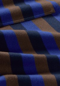 Tessuto di lana con strisce diagonali in blu scuro, blu chiaro e marrone, con una trama strutturata che conferisce profondità al motivo.