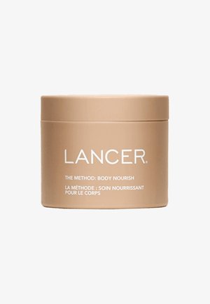 Ronde beige container met een gladde matte afwerking. De voorzijde van het etiket bevat witte tekst: "LANCER THE METHOD: BODY NOURISH" in twee talen.