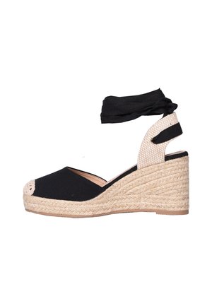 Sandalo espadrille con zeppa con punta in tessuto nero, tacco intrecciato beige e cinturino nero alla caviglia su sfondo bianco.