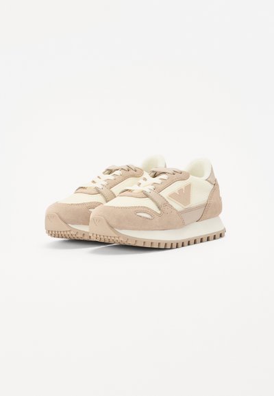 Zapatillas deportivas en tonos beige y crema, con materiales de ante y malla, punta redondeada, acentos contrastantes y suela de goma texturizada.