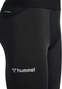 Schwarze atmungsaktive Leggings mit glatter Textur, ausgestattet mit einem weißen Hummel-Logo und einem enganliegenden Design für aktive Kleidung.
