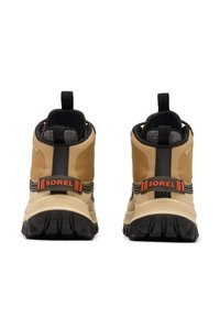 Bottes d'été imperméables couleur camel avec accents noirs, tissu texturé et logo Sorel orange. Comprend une semelle extérieure en caoutchouc et une bride pour un enfilage facile.