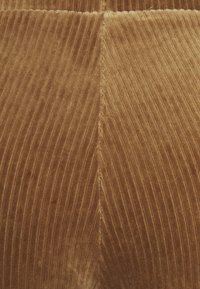 Velvet fabric in warm brown color, featuring vertical ribbed texture and a seam running through the middle. Soft, plush appearance.