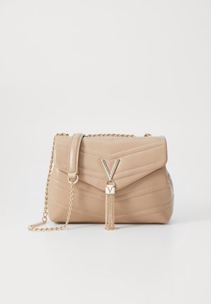 Beige quiltet taske med guld kæderem, V-formet guldlås og guldtassel detalje på hvid baggrund.