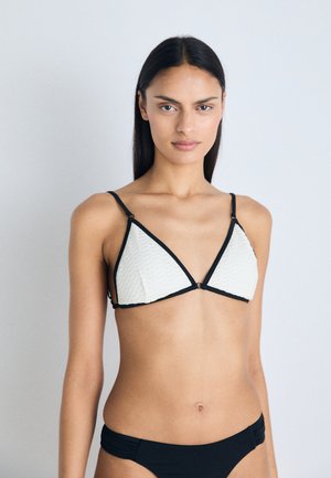 White triangular bikini top with textured fabric, black trim, and spaghetti straps. Black bikini bottom with slight ruching at the sides.
