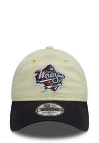 Beige cotton cap with a black bill, featuring an embroidered "World Series" logo in red, white, and blue on the front. Adjustable strap.