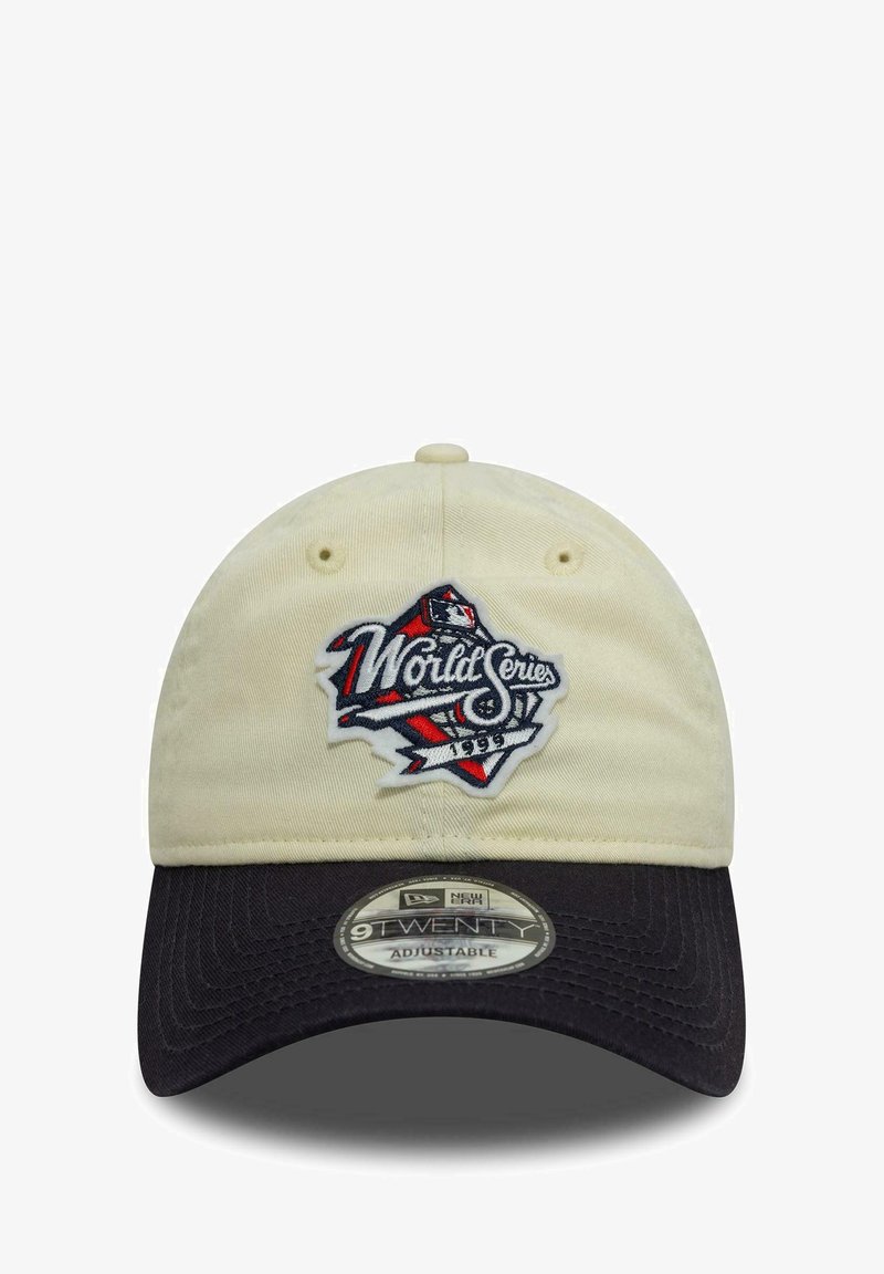 Beige cotton cap with a black bill, featuring an embroidered "World Series" logo in red, white, and blue on the front. Adjustable strap.