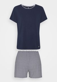 Chemise à manches courtes bleu marine avec un col à bord blanc, associée à un short blanc à fines rayures horizontales bleu marine.