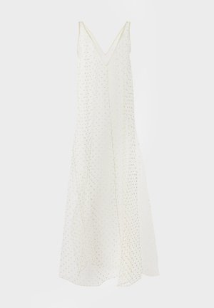 Bílé šaty bez rukávů s výstřihem do V a vzorem zlatých puntíků, splývavá látka a délka ke kotníkům.