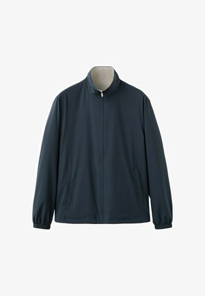 Marineblauwe jas met rits en opstaande kraag, elastische manchetten en twee zijzakken, afgebeeld tegen een neutrale achtergrond.