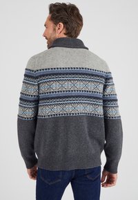 Maglione lavorato a maglia spessa di colore grigio con un collo a scialle e polsini a costine. Presenta un girocollo decorato con un motivo che include accenti blu e neri.