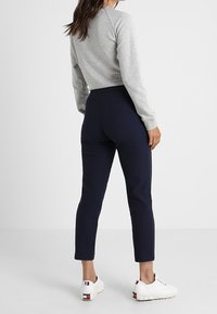Un haut gris à manches longues assorti à un pantalon ajusté bleu marine et des baskets blanches. Présente un design décontracté, une texture douce et une coupe longueur cheville.