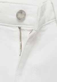 White denim fabric featuring a close-up view of a silver button and zipper with gold-colored teeth, showcasing fine stitching details.