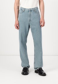 Jeans din denim de un albastru deschis, cu o croială lejeră, talie înaltă și cinci buzunare. Include un sistem de închidere cu buton și fermoar și o textură ușor estompată.