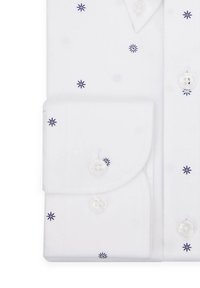 Biała koszula z niebieskimi haftowanymi gwiazdkami, z kołnierzykiem na guziki i mankietami, oraz przezroczystymi plastikowymi guzikami. Gładka bawełniana tkanina.
