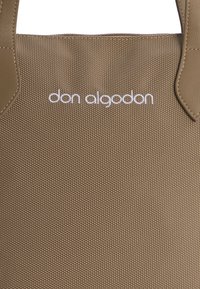 Bolso tote marrón Texturizado con acentos de cuero liso. Presenta el logo blanco "don algodon". Forma rectangular con asas cortas.