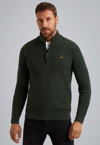 Dunkelgrüner gestrickter Pullover mit hohem Kragen, Viertel-Reißverschluss, strukturiertem Muster und gerippten Bündchen und Saum. Goldenes Logo-Element auf der Brust.