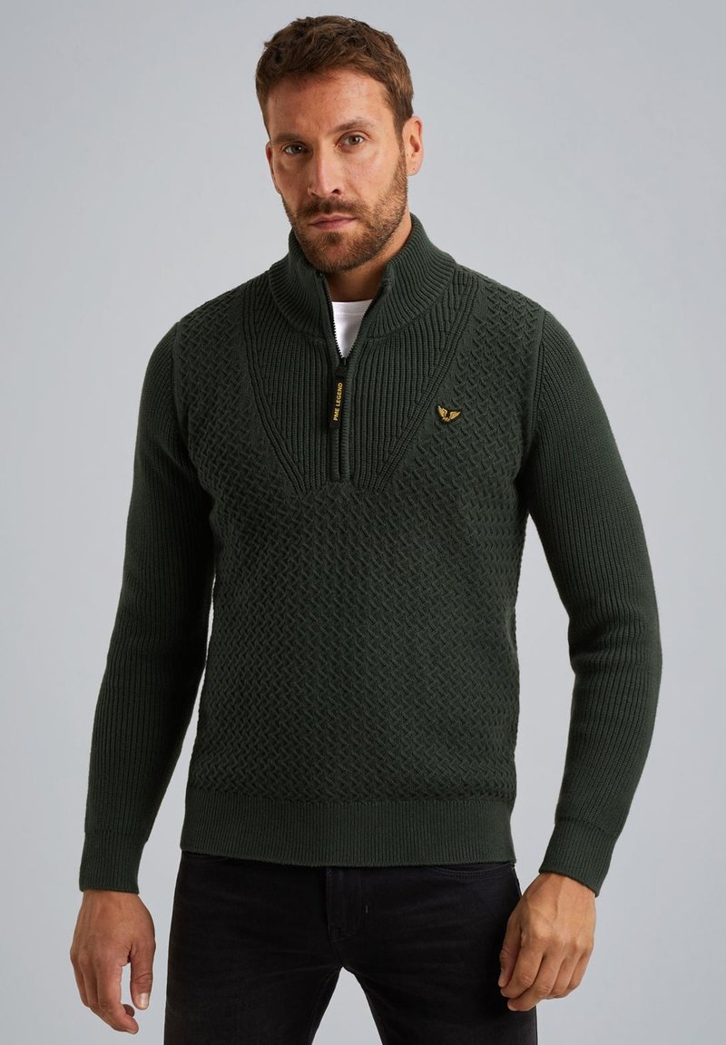 Dunkelgrüner gestrickter Pullover mit hohem Kragen, Viertel-Reißverschluss, strukturiertem Muster und gerippten Bündchen und Saum. Goldenes Logo-Element auf der Brust.
