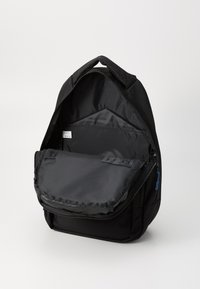 Black backpack with a zipped closure, fabric material, front flap pocket, adjustable shoulder straps, and a blue zipper accent. Inside is lined.