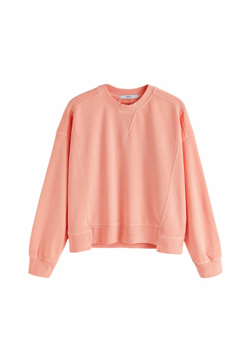 Sweatshirt de couleur pêche, design court, poignets et ourlet côtelés, texture douce, avec un col rond et des manches raglan.