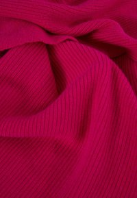 Fuchsia gestrickter Stoff mit geripptem Textur, der Falten und Knicke aufweist und ein weiches und einladendes Aussehen schafft.