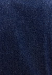 Tissu en denim bleu foncé avec texture de tissage diagonal visible et variations subtiles de couleur sous l'éclairage.
