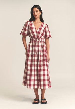 Rood en wit geruit midi-jurk met pofmouwen en een V-hals, met een trekkoord in de taille en een vloeiende rok, gemaakt van lichtgewicht stof.