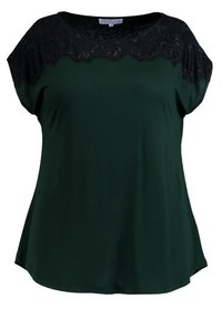 Blusa verde oscura con cuello redondo y mangas cortas, con un encaje negro superpuesto en los hombros. Textura de tejido suave.