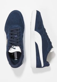 Marineblaue Wildleder-Sneaker mit einem weißen Streifen, Gummisohle, Schnürdesign und Logo-Elementen an der Zunge und der Seite.