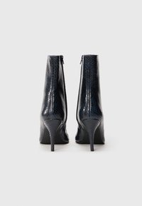 Botas de tobillo azul marino con un patrón de serpiente brillante y texturizado, altos tacones de aguja y cremalleras ocultas en la parte trasera.