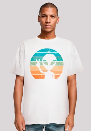 White cotton t-shirt featuring a distressed graphic of an alien and peace sign against a gradient circle of teal and orange stripes.