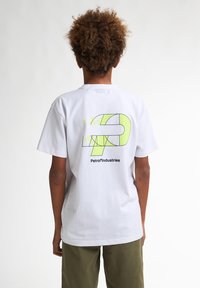 Tricou alb din bumbac, cu un design geometric verde neon și textul "Petrol Industries" pe spate. Mâneci scurte și croială lejeră.