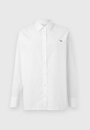 Valkoinen pitkähihaista paitaa, joka on valmistettu puuvillasta. Paita sisältää nappikauluksen, etunappion ja pienen brodeeratun logon vasemmassa rinnassa.