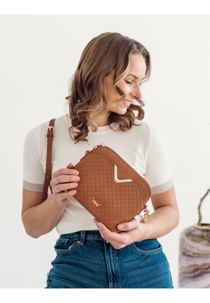 Braune gepolsterte Crossbody-Tasche mit goldenen Hardware-Details. Verfügt über einen oberen Reißverschluss und einen verstellbaren Riemen. Die strukturierte Oberfläche ist detailliert und modern.