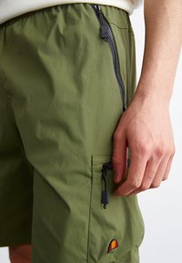 Shorts cargo verts en tissu léger, dotés d'une poche zippée sur le côté, d'une taille élastique et d'un petit logo brodé sur le côté.