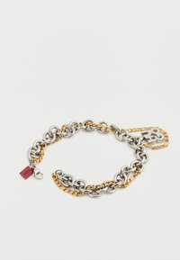 Βραχιόλι αλυσίδας από ασήμι και χρυσό με συνδυασμό υφασμένων και λείας συνδέσμων, με κόκκινη ετικέτα λογότυπου και κούμπωμα κλειδώματος.