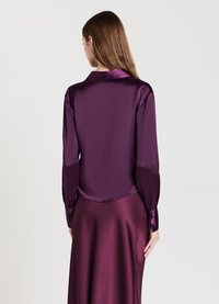 Blusa viola lucida a maniche lunghe con colletto classico e polsini con bottoni, caratterizzata da una texture liscia e un'elegante caduta.