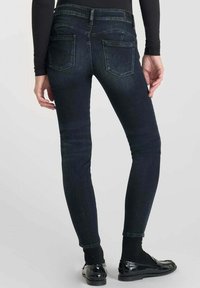 Jeans ajustados en denim de lavado oscuro, con bolsillos traseros en ángulo y un diseño distintivo, de corte slim y una tela suave y con textura.
